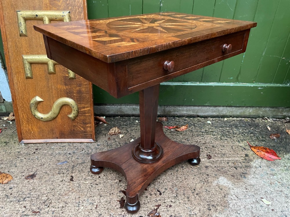 A nineteenth-century rectangular rosewood side table featuring a starburst specimen wood inlaid top set on a pedestal base with a quadform platform. View X