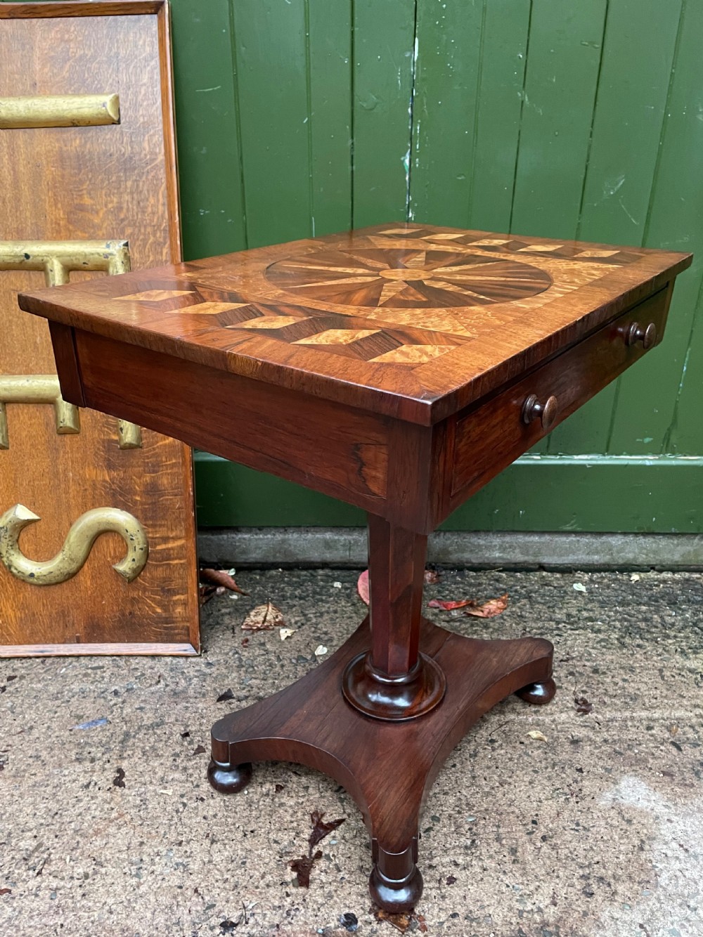 A nineteenth-century rectangular rosewood side table featuring a starburst specimen wood inlaid top set on a pedestal base with a quadform platform. View XV