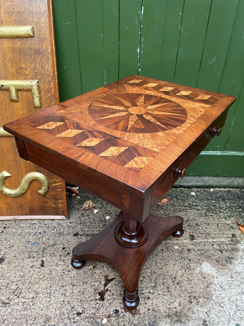 A nineteenth-century rectangular rosewood side table featuring a starburst specimen wood inlaid top set on a pedestal base with a quadform platform. View XVIII