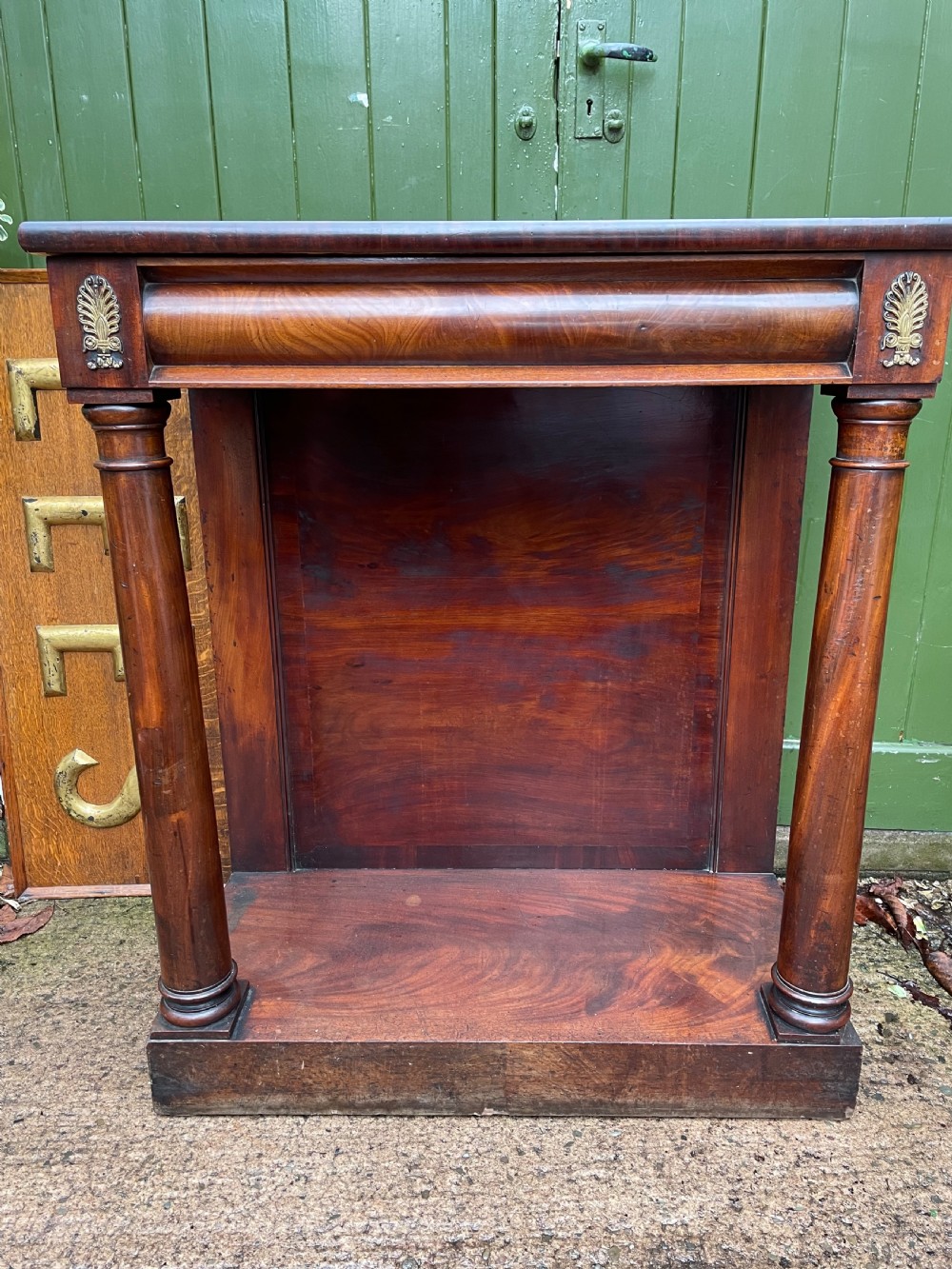 Early 19th-century George IV mahogany console table featuring cylindrical front columns, brass mounts, a plinth base, and a flame mahogany backdrop. View VIII