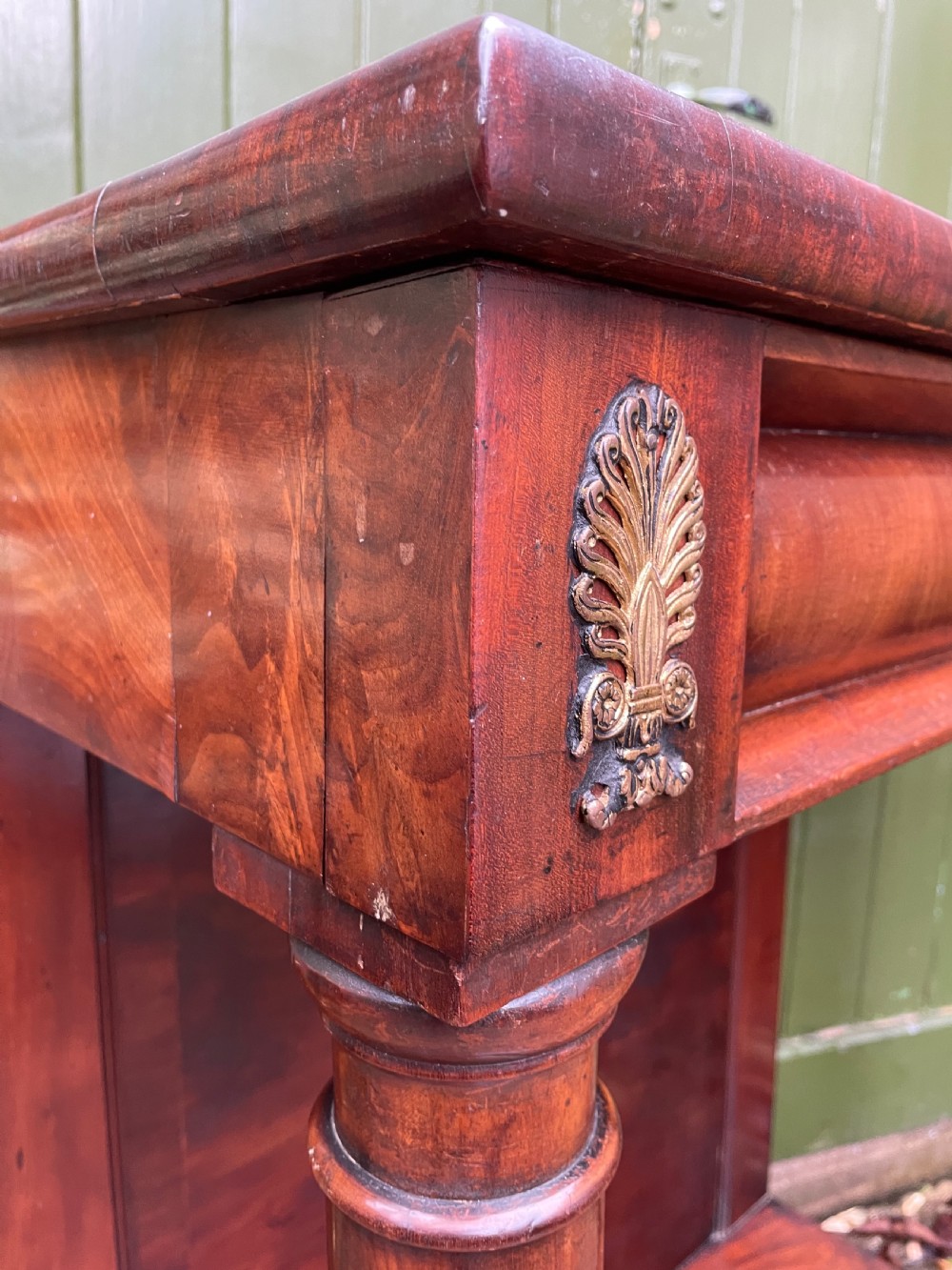 Early 19th-century George IV mahogany console table featuring cylindrical front columns, brass mounts, a plinth base, and a flame mahogany backdrop. View XI