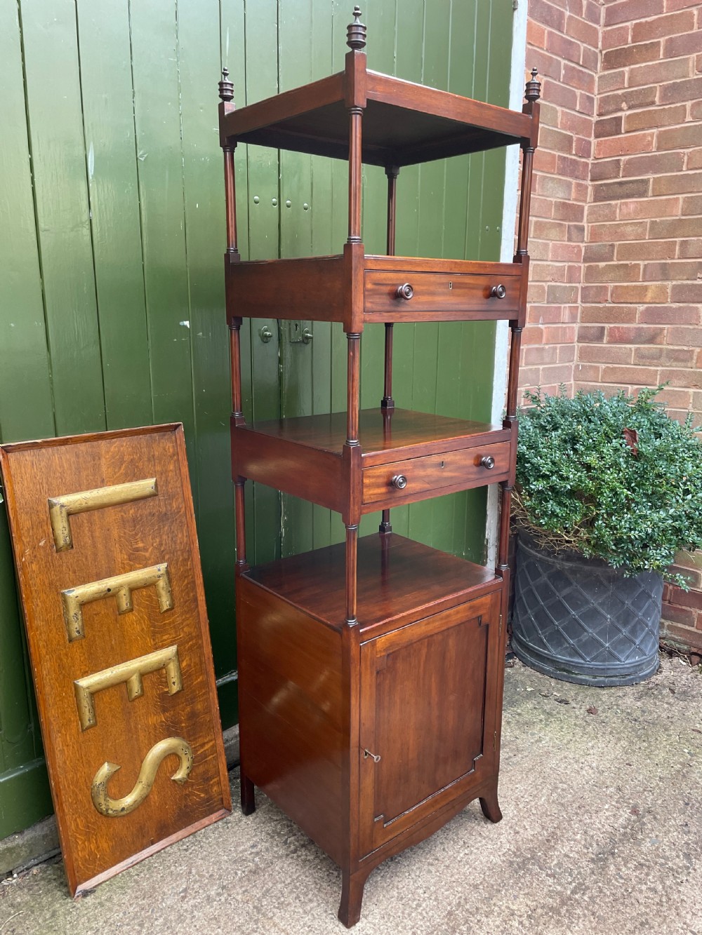 A tall late eighteenth-century George III mahogany etagere featuring open shelves, turned column supports, two drawers, and a lower enclosed cupboard. View III