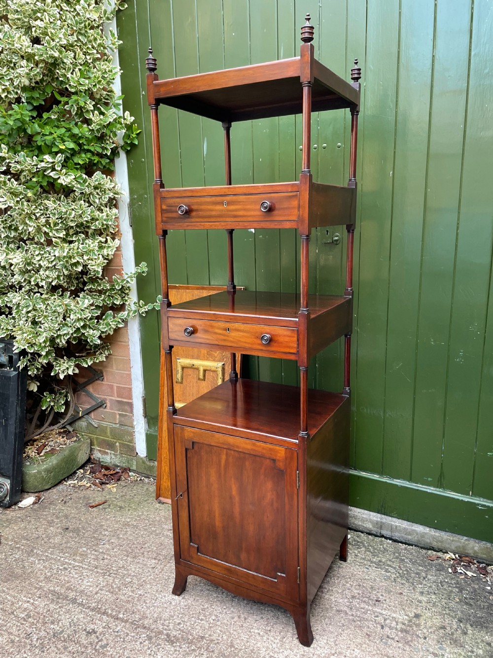 A tall late eighteenth-century George III mahogany etagere featuring open shelves, turned column supports, two drawers, and a lower enclosed cupboard. View V