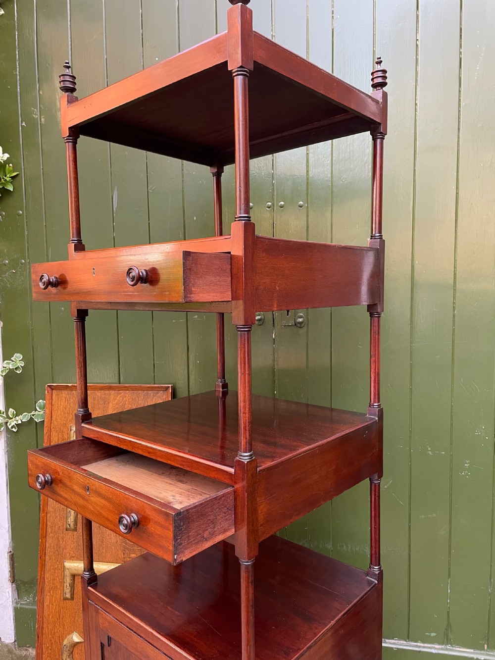 A tall late eighteenth-century George III mahogany etagere featuring open shelves, turned column supports, two drawers, and a lower enclosed cupboard. View XVI