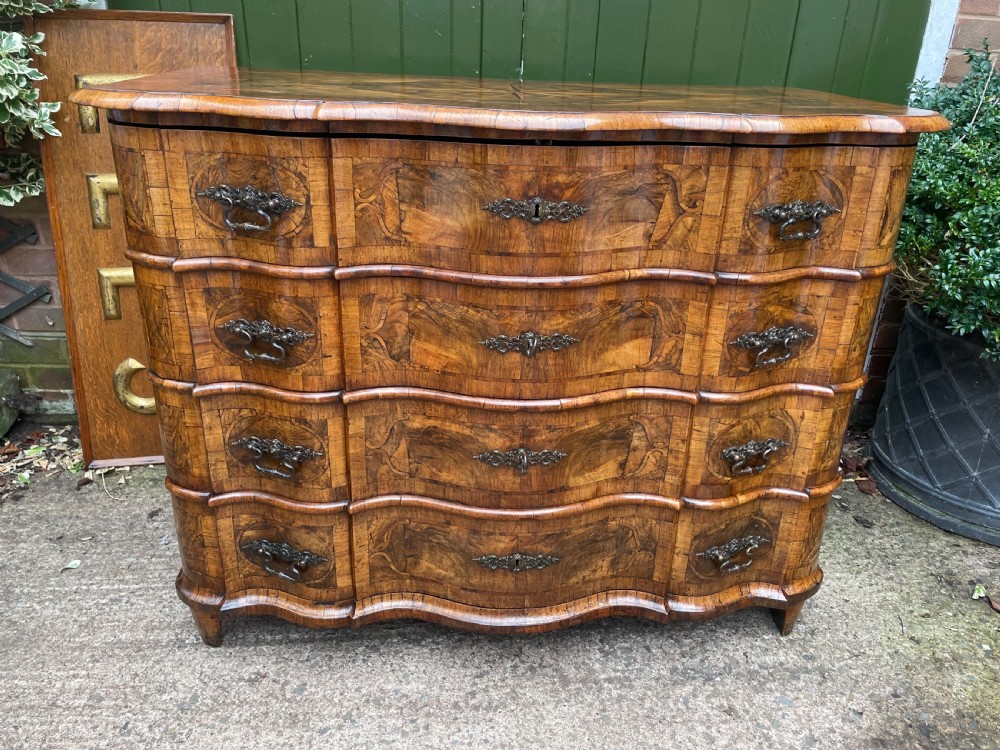 A mid-18th-century German Baroque walnut commode featuring a shaped serpentine front, four long drawers with figured wood veneers, and ornate cast brass handles. View III