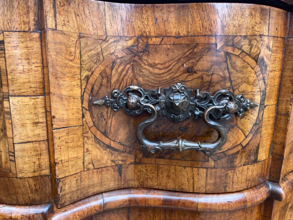 A mid-18th-century German Baroque walnut commode featuring a shaped serpentine front, four long drawers with figured wood veneers, and ornate cast brass handles. View VIII
