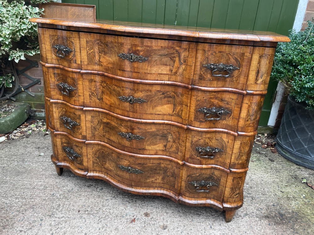 A mid-18th-century German Baroque walnut commode featuring a shaped serpentine front, four long drawers with figured wood veneers, and ornate cast brass handles. View XIII