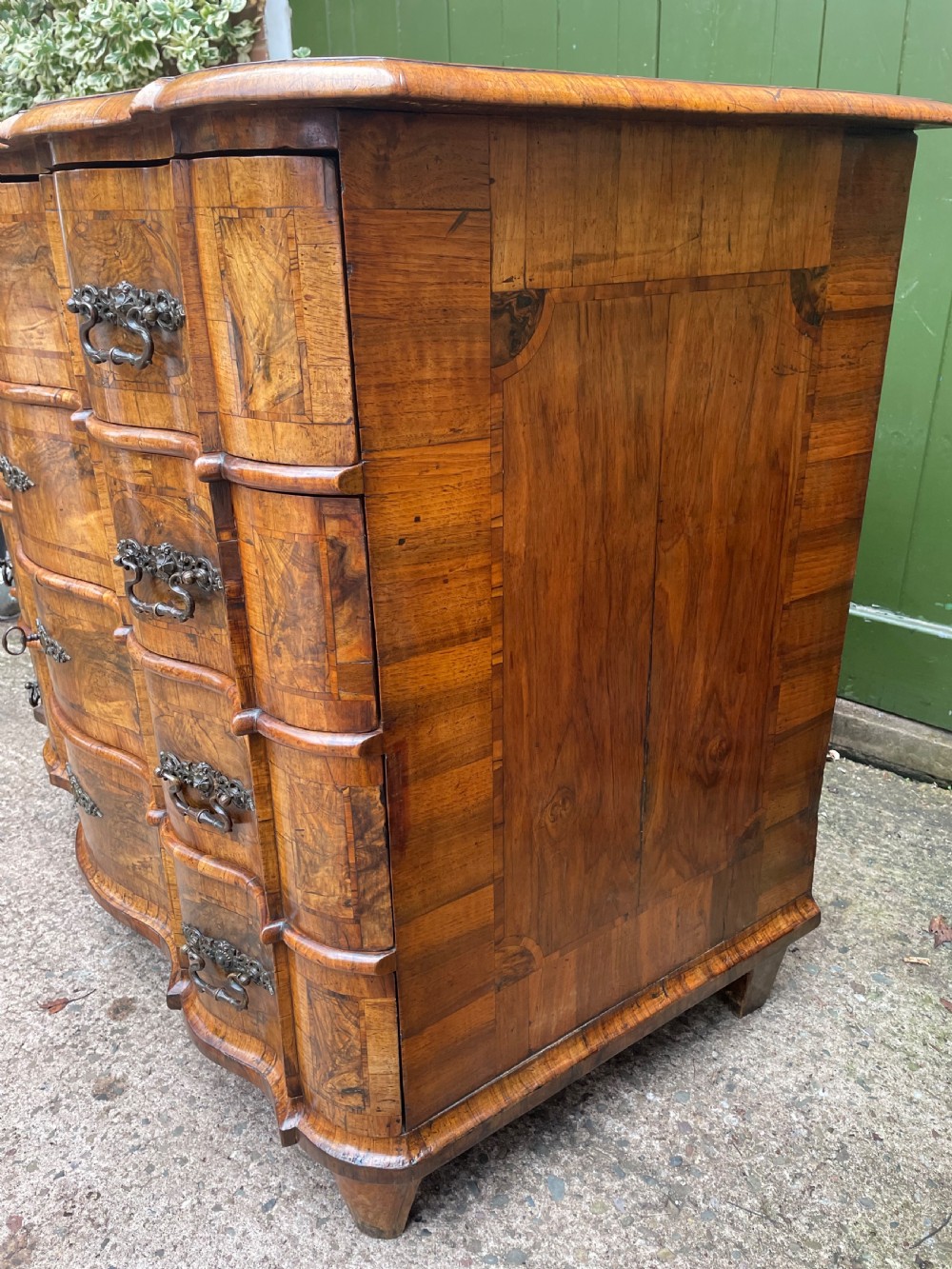 A mid-18th-century German Baroque walnut commode featuring a shaped serpentine front, four long drawers with figured wood veneers, and ornate cast brass handles. View XIV