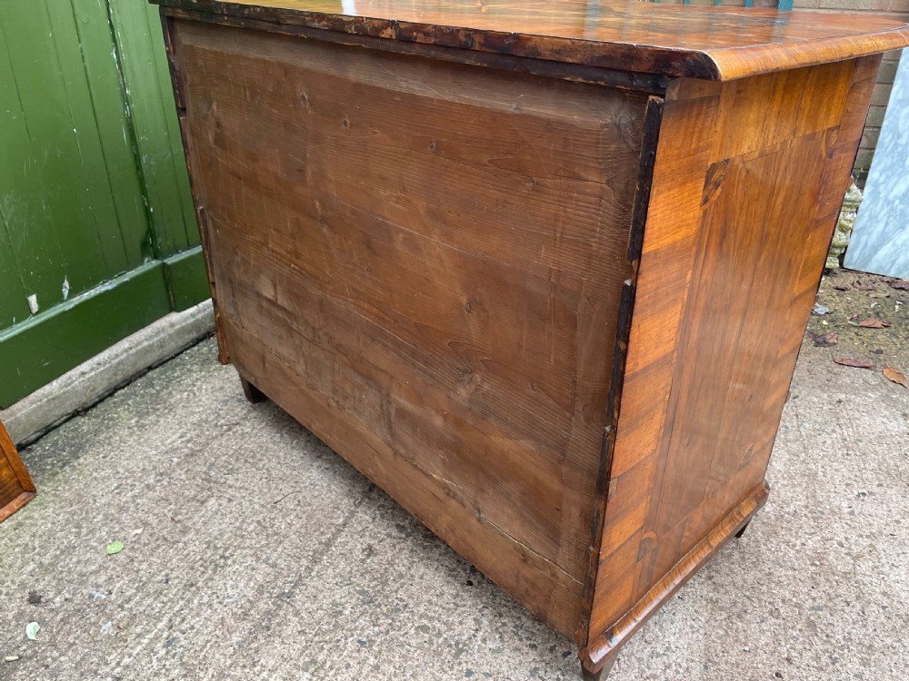 A mid-18th-century German Baroque walnut commode featuring a shaped serpentine front, four long drawers with figured wood veneers, and ornate cast brass handles. View XXIX