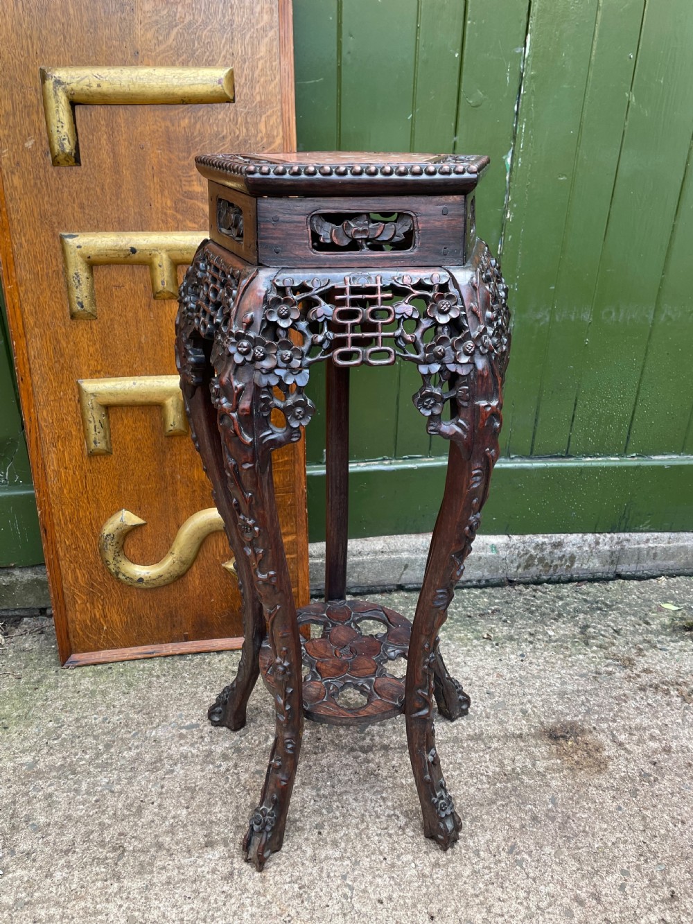 A late nineteenth-century Chinese carved dark hardwood plant stand featuring intricate floral openwork aprons, slender curved legs, and a lower circular tier. View II