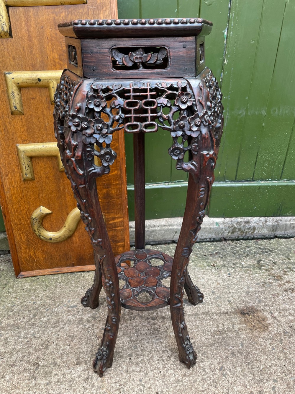A late nineteenth-century Chinese carved dark hardwood plant stand featuring intricate floral openwork aprons, slender curved legs, and a lower circular tier. View IV