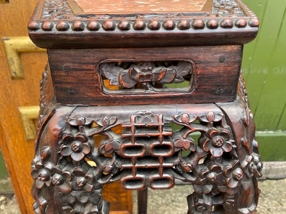 A late nineteenth-century Chinese carved dark hardwood plant stand featuring intricate floral openwork aprons, slender curved legs, and a lower circular tier. View V