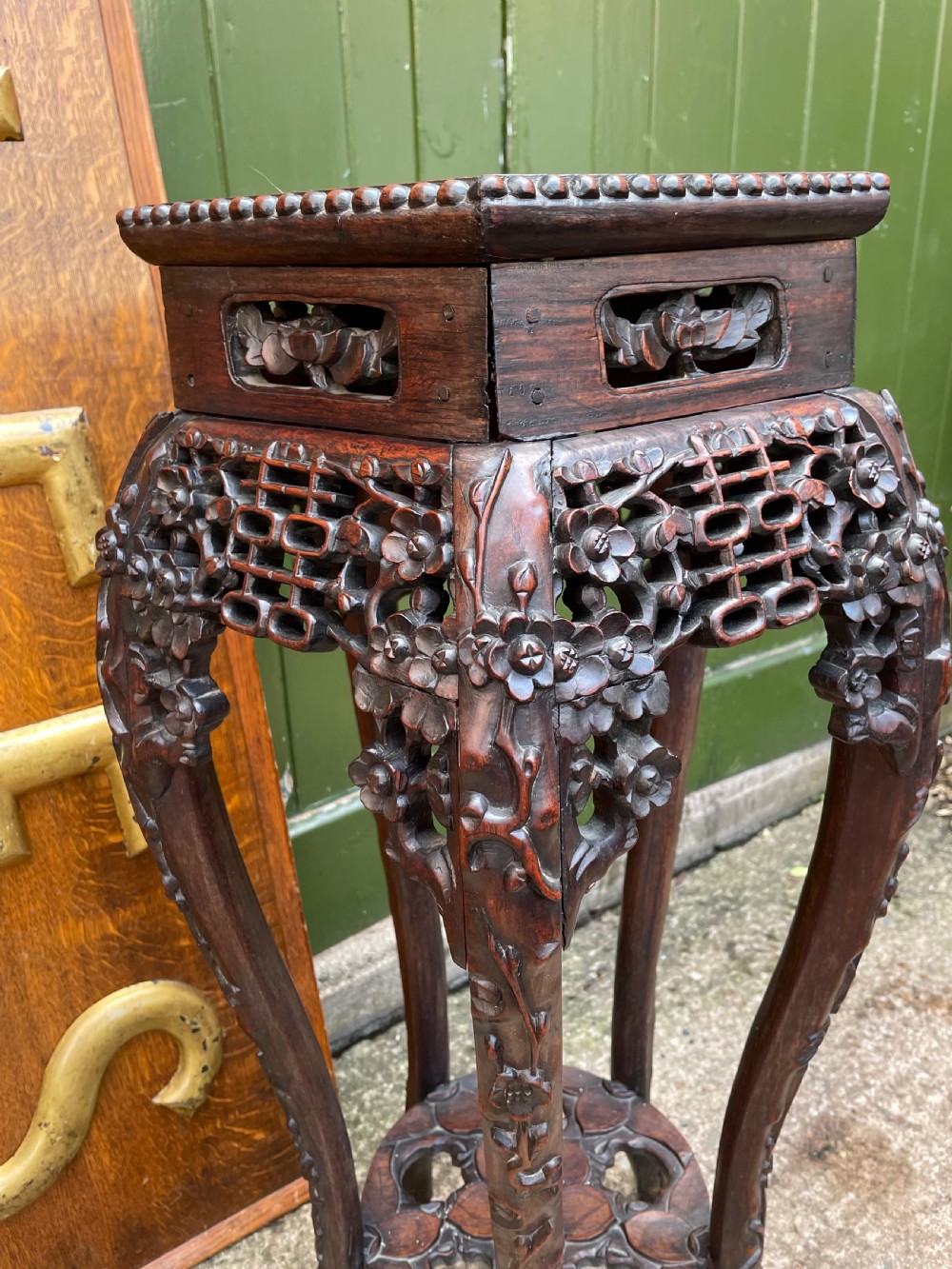 A late nineteenth-century Chinese carved dark hardwood plant stand featuring intricate floral openwork aprons, slender curved legs, and a lower circular tier. View VI