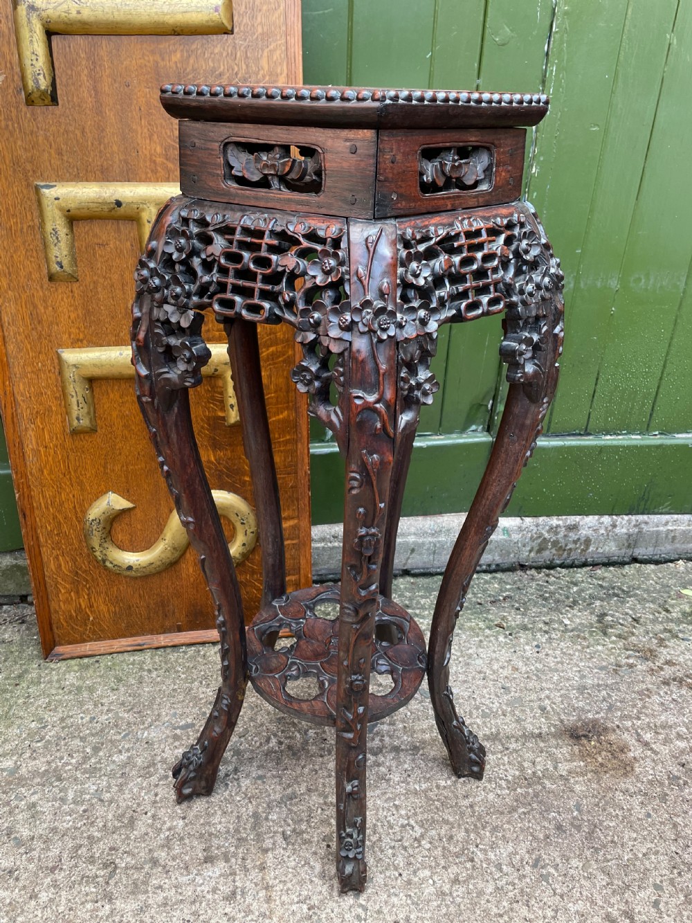 A late nineteenth-century Chinese carved dark hardwood plant stand featuring intricate floral openwork aprons, slender curved legs, and a lower circular tier. View VII