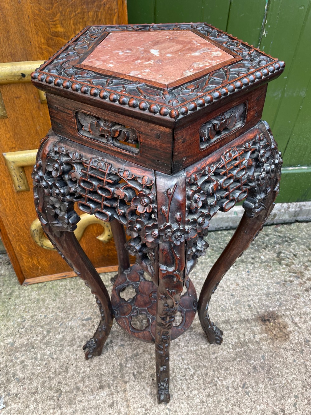 A late nineteenth-century Chinese carved dark hardwood plant stand featuring intricate floral openwork aprons, slender curved legs, and a lower circular tier. View VIII