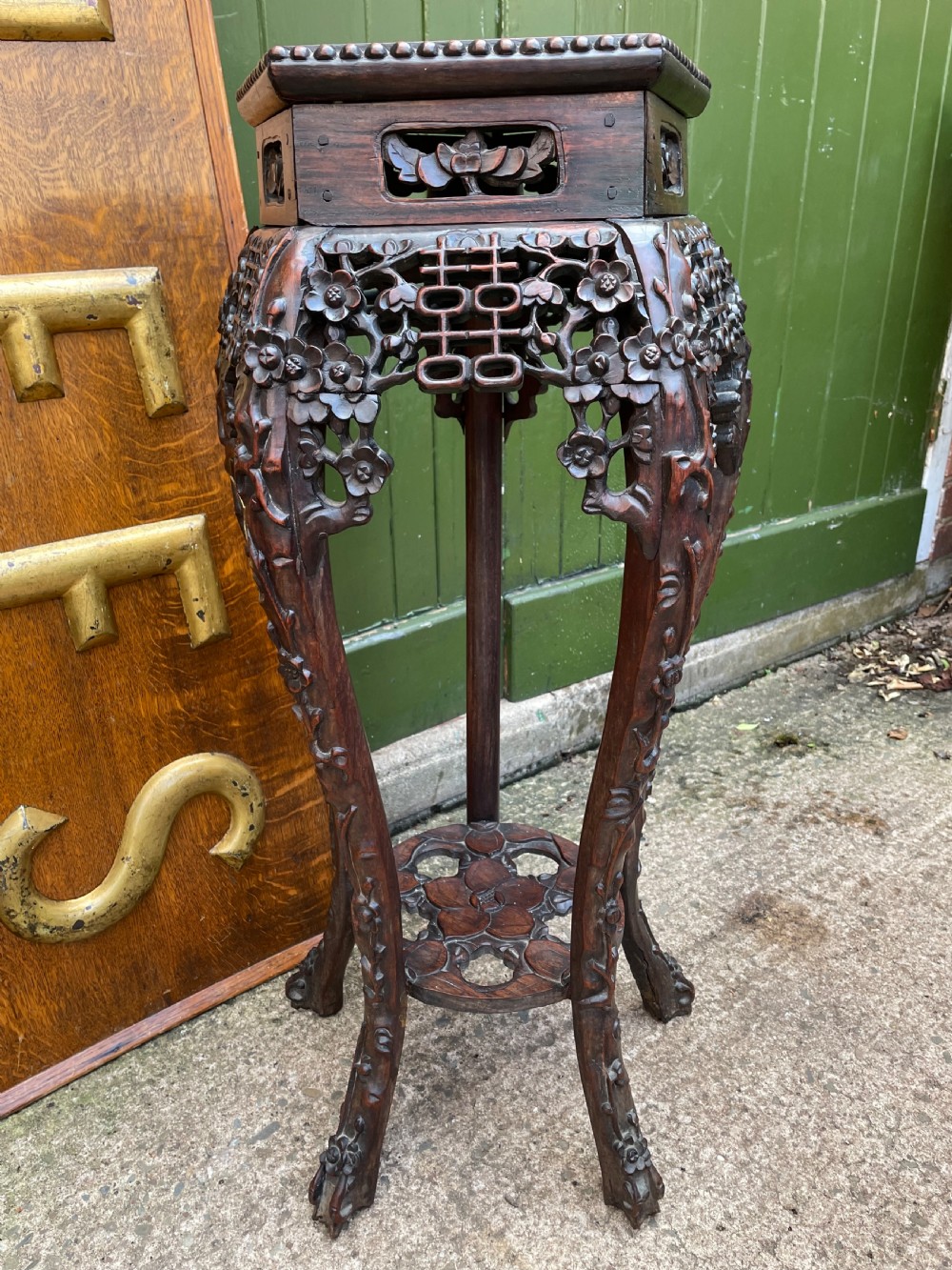 A late nineteenth-century Chinese carved dark hardwood plant stand featuring intricate floral openwork aprons, slender curved legs, and a lower circular tier. View IX
