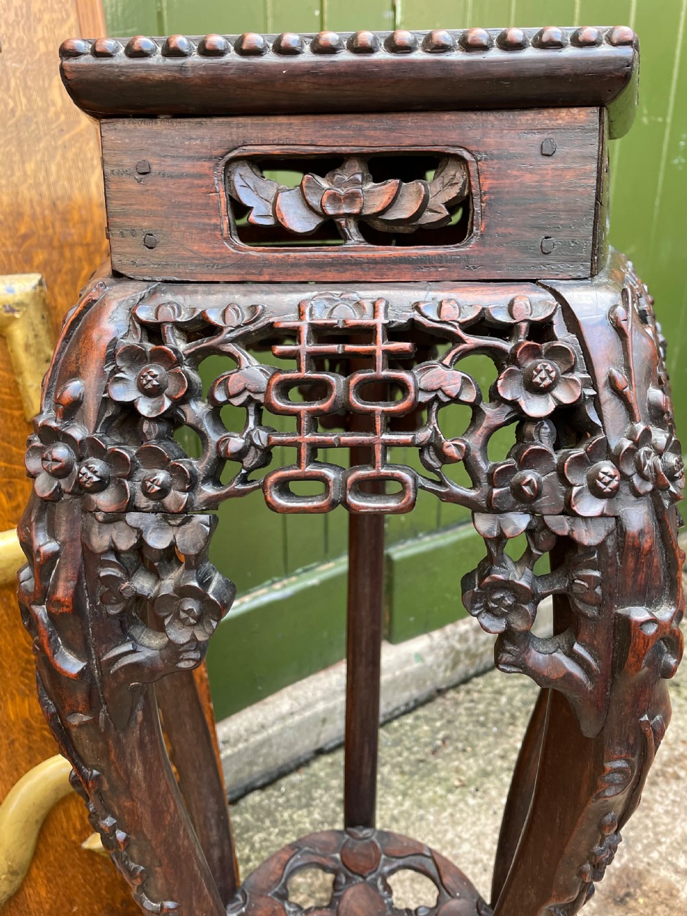A late nineteenth-century Chinese carved dark hardwood plant stand featuring intricate floral openwork aprons, slender curved legs, and a lower circular tier. View X