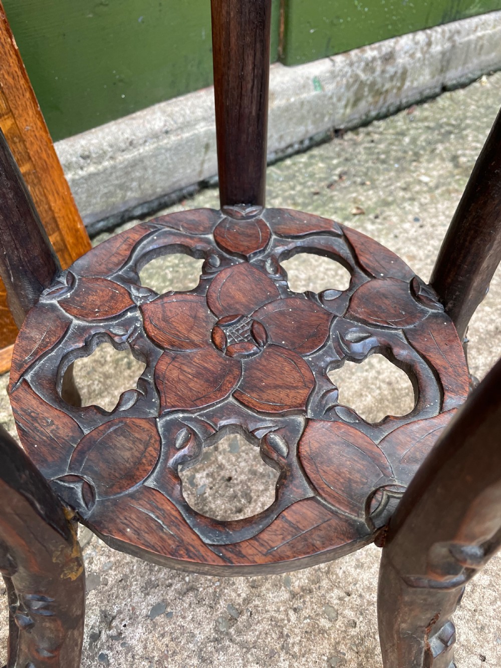 A late nineteenth-century Chinese carved dark hardwood plant stand featuring intricate floral openwork aprons, slender curved legs, and a lower circular tier. View XI