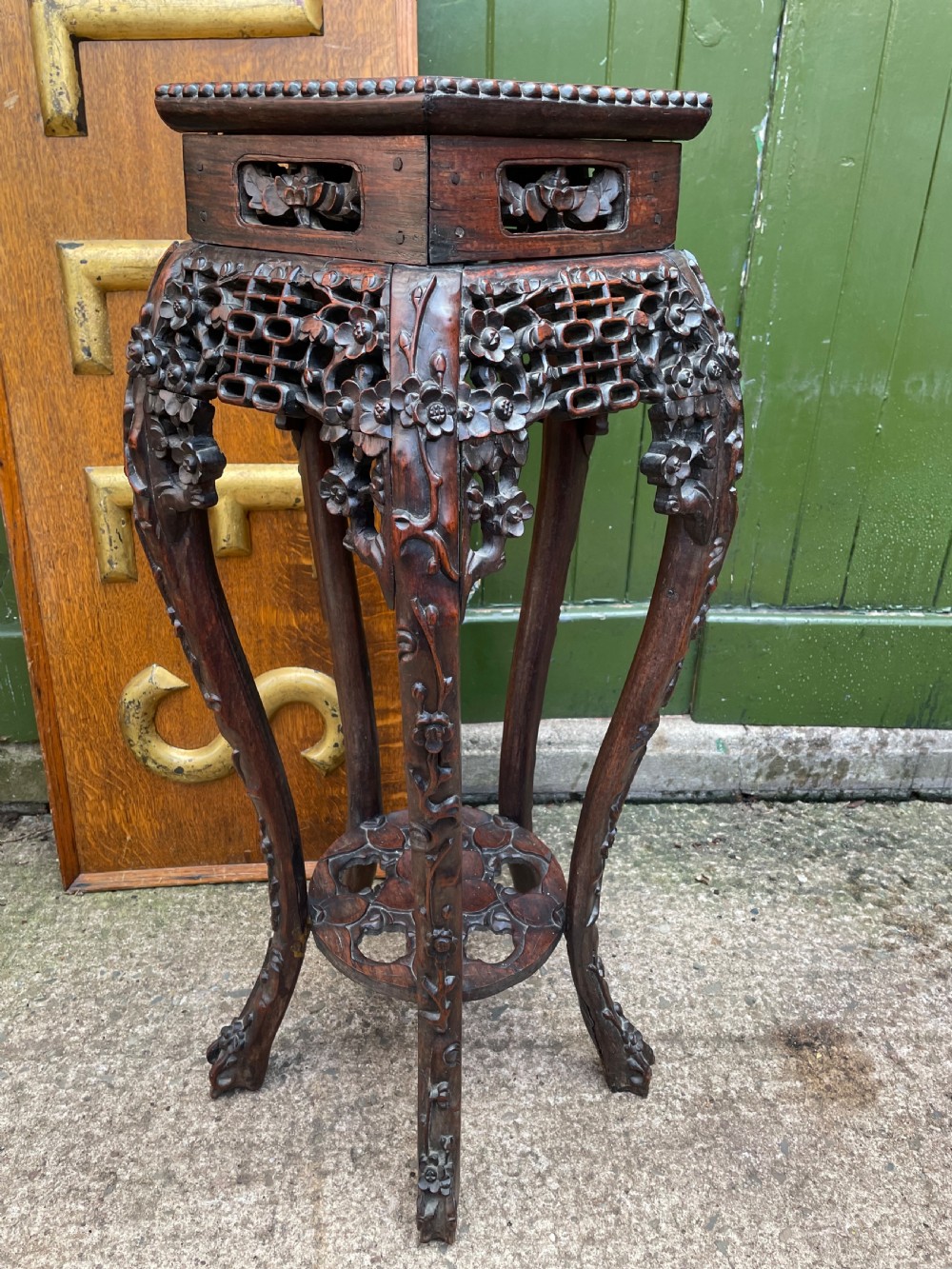 A late nineteenth-century Chinese carved dark hardwood plant stand featuring intricate floral openwork aprons, slender curved legs, and a lower circular tier. View XII
