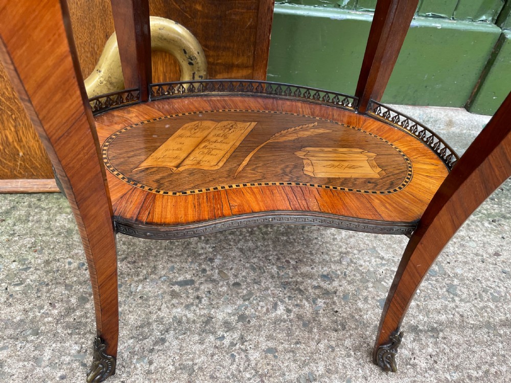 A late nineteenth-century French oval marquetry table featuring three drawers with floral inlay, a pierced brass gallery top, and a lower shelf decorated with a marquetry book design. View IX