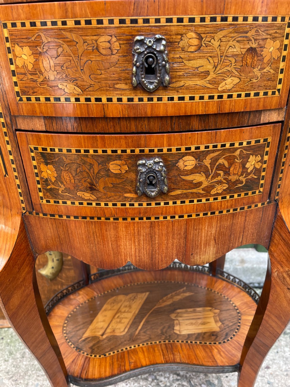 A late nineteenth-century French oval marquetry table featuring three drawers with floral inlay, a pierced brass gallery top, and a lower shelf decorated with a marquetry book design. View XVIII