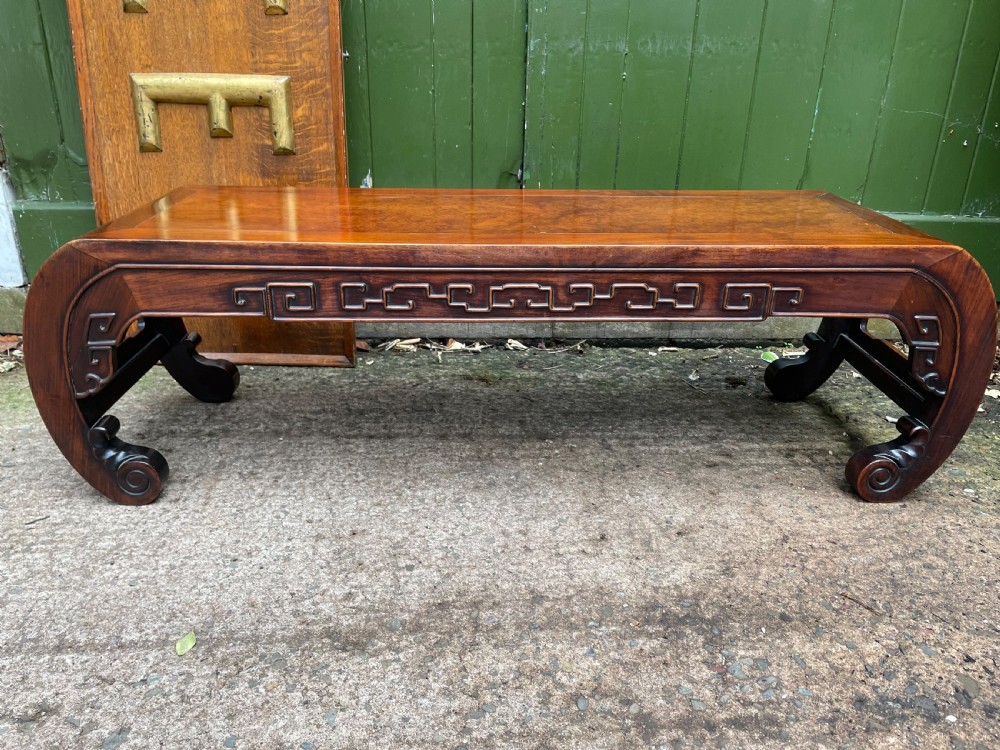 A low Chinese Qing Dynasty hardwood kang table featuring carved key-fret aprons and inward-curved scroll legs. View II