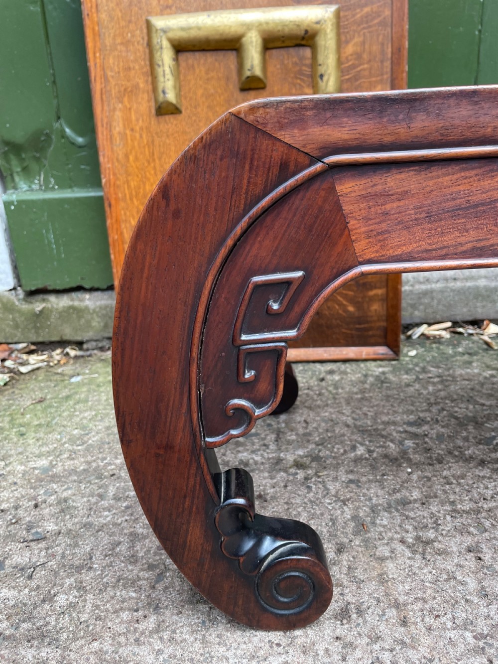 A low Chinese Qing Dynasty hardwood kang table featuring carved key-fret aprons and inward-curved scroll legs. View V