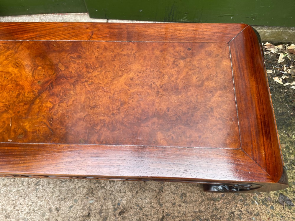 A low Chinese Qing Dynasty hardwood kang table featuring carved key-fret aprons and inward-curved scroll legs. View IX