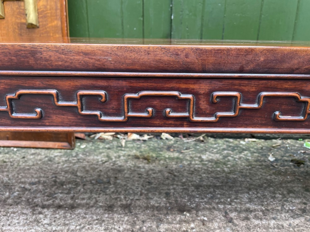 A low Chinese Qing Dynasty hardwood kang table featuring carved key-fret aprons and inward-curved scroll legs. View XIII