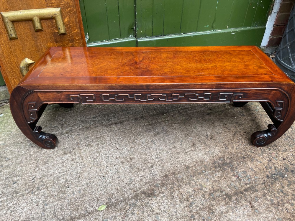 A low Chinese Qing Dynasty hardwood kang table featuring carved key-fret aprons and inward-curved scroll legs. View XV