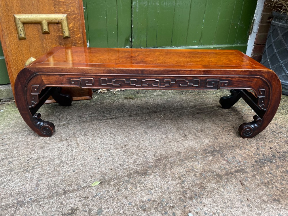 A low Chinese Qing Dynasty hardwood kang table featuring carved key-fret aprons and inward-curved scroll legs. View XVI
