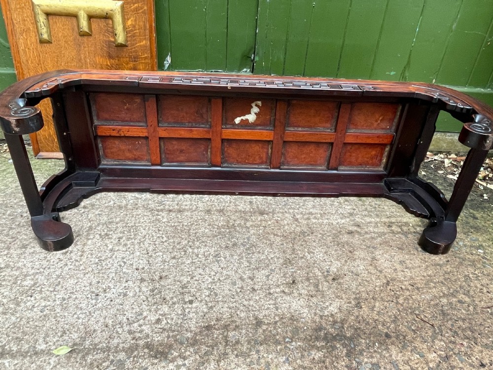 A low Chinese Qing Dynasty hardwood kang table featuring carved key-fret aprons and inward-curved scroll legs. View XVII