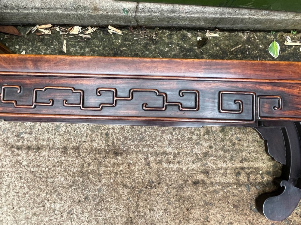 A low Chinese Qing Dynasty hardwood kang table featuring carved key-fret aprons and inward-curved scroll legs. View XVIII
