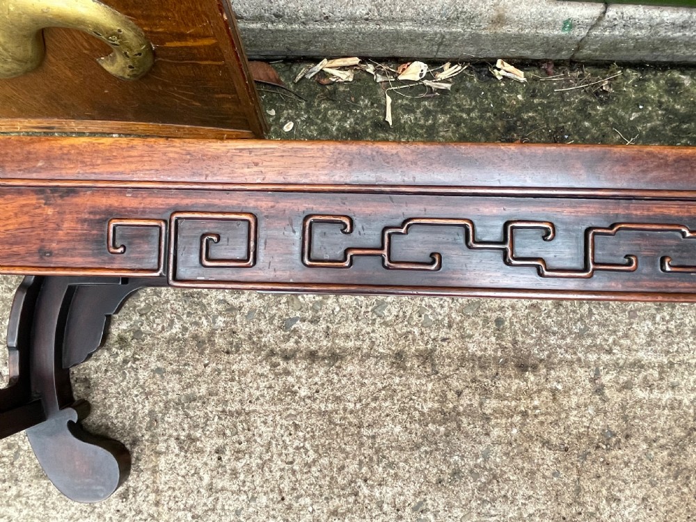 A low Chinese Qing Dynasty hardwood kang table featuring carved key-fret aprons and inward-curved scroll legs. View XXI