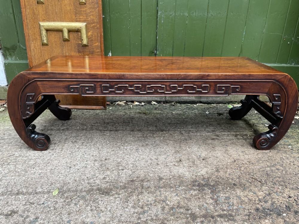 A low Chinese Qing Dynasty hardwood kang table featuring carved key-fret aprons and inward-curved scroll legs. View XXII