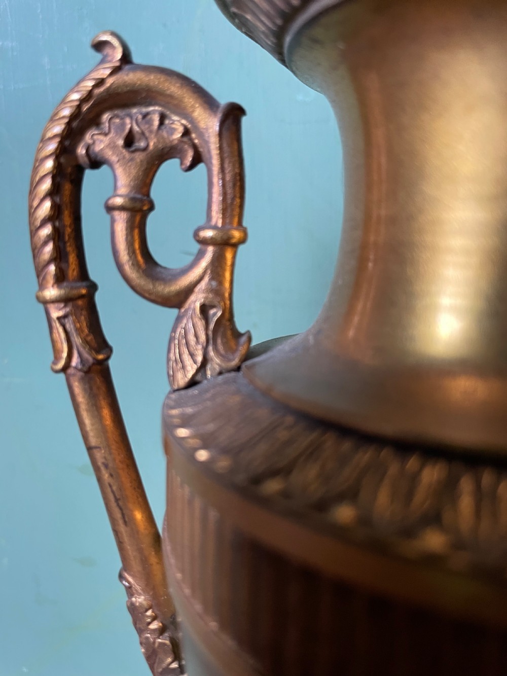 A pair of early 19th-century French gilt-bronze Neoclassical urns featuring scrolled handles, acanthus leaf relief, and diaper-patterned cylindrical plinths. View XIV