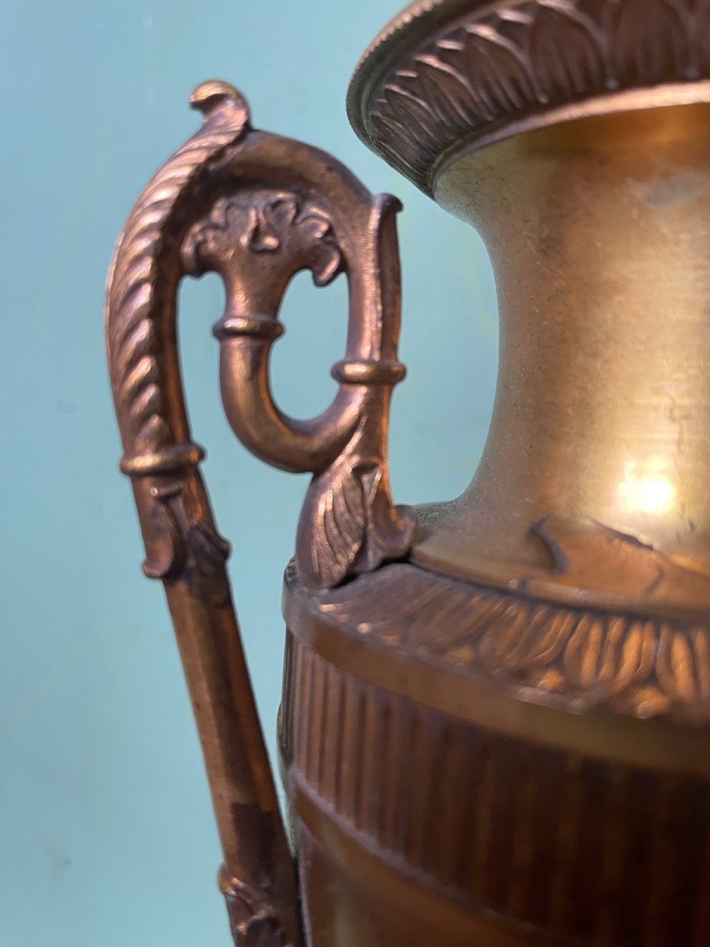 A pair of early 19th-century French gilt-bronze Neoclassical urns featuring scrolled handles, acanthus leaf relief, and diaper-patterned cylindrical plinths. View XXI