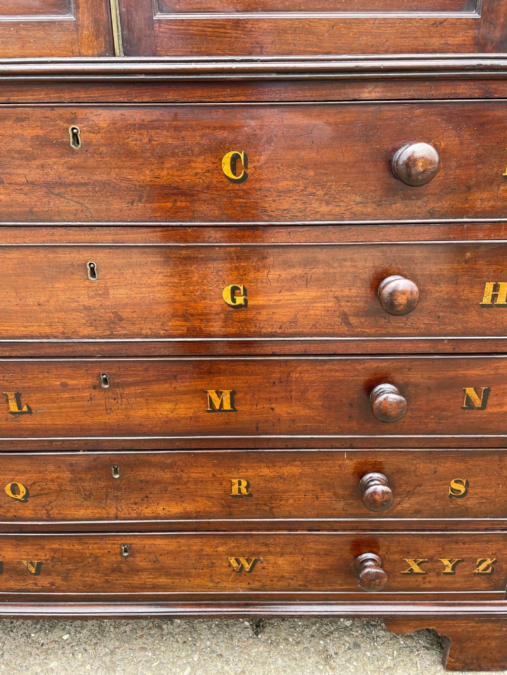 A late eighteenth-century George III mahogany estate cabinet featuring upper panel doors above drawers with gilded alphabetical lettering. View VI