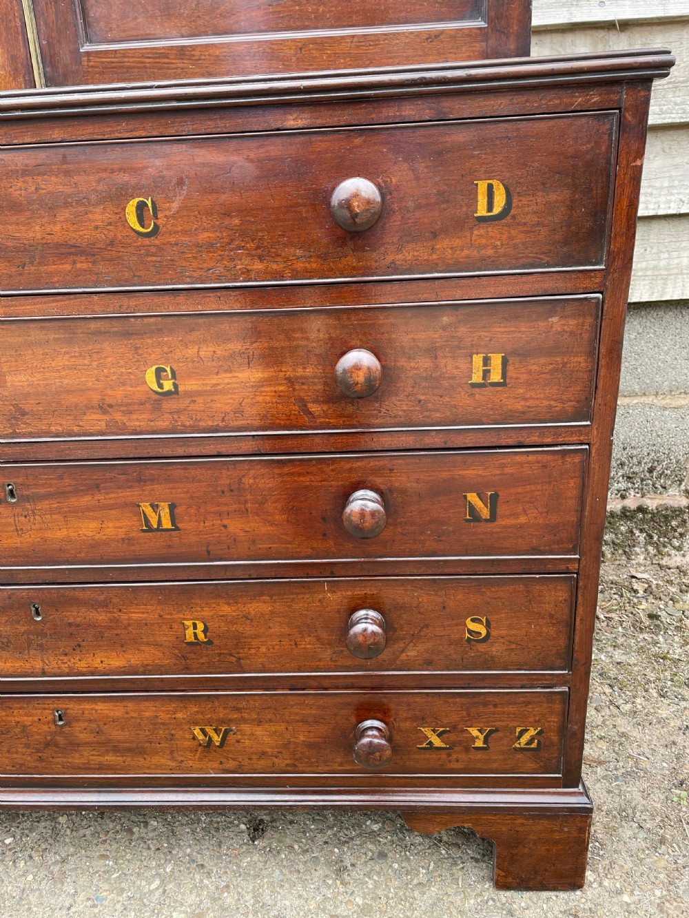 A late eighteenth-century George III mahogany estate cabinet featuring upper panel doors above drawers with gilded alphabetical lettering. View VII