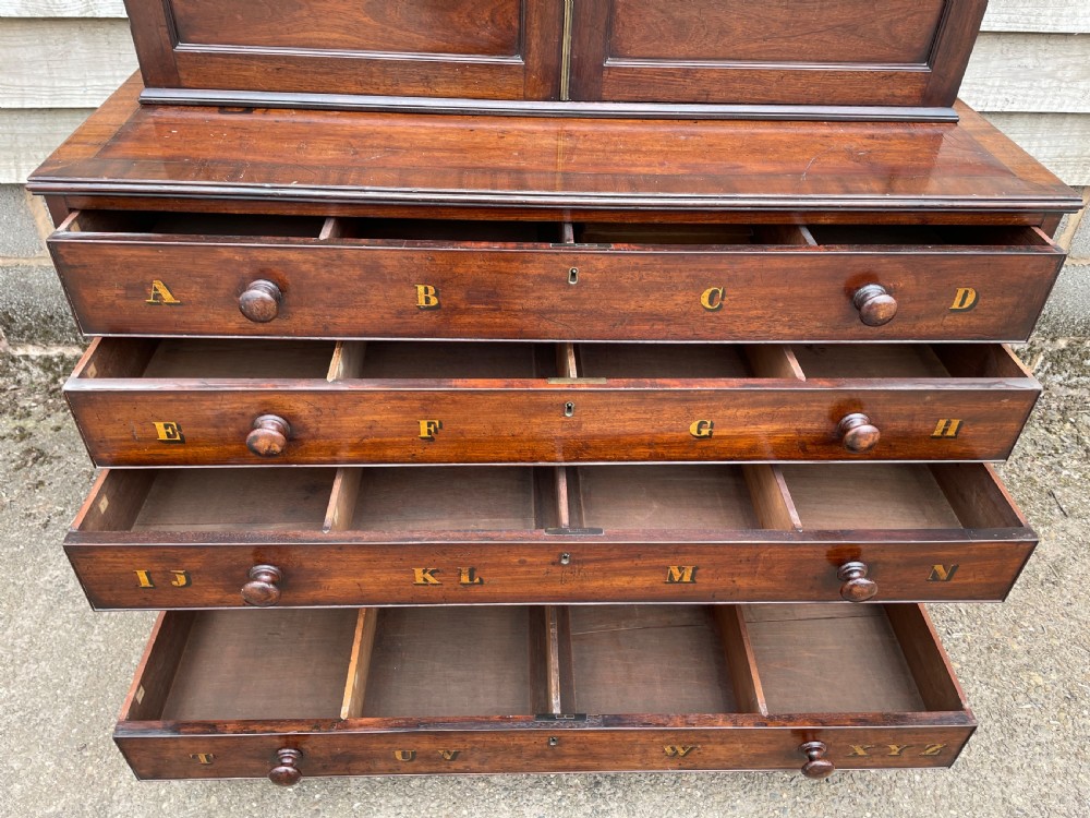A late eighteenth-century George III mahogany estate cabinet featuring upper panel doors above drawers with gilded alphabetical lettering. View XI