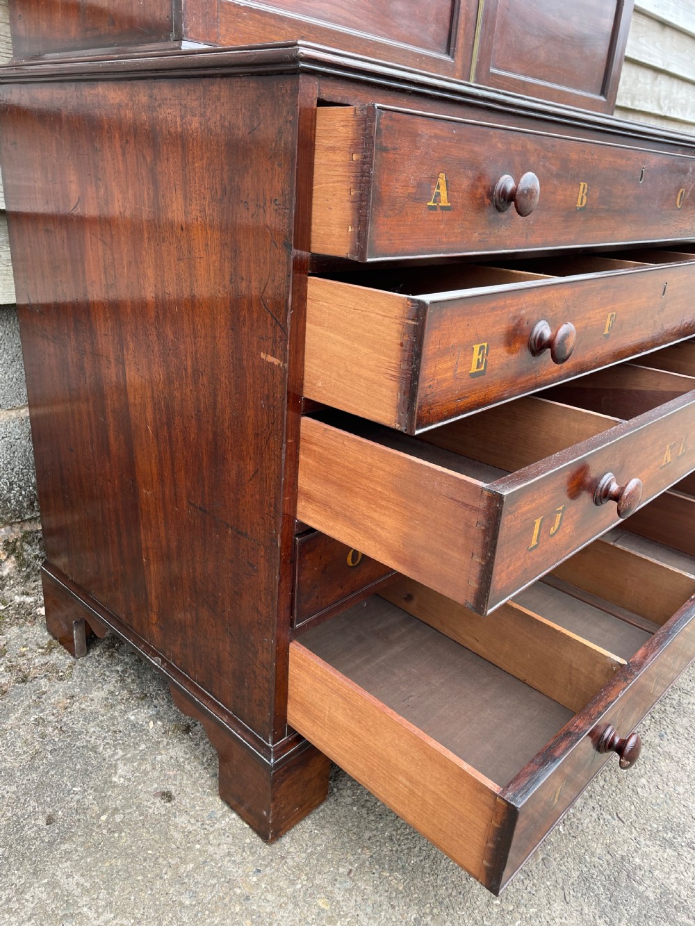 A late eighteenth-century George III mahogany estate cabinet featuring upper panel doors above drawers with gilded alphabetical lettering. View XII