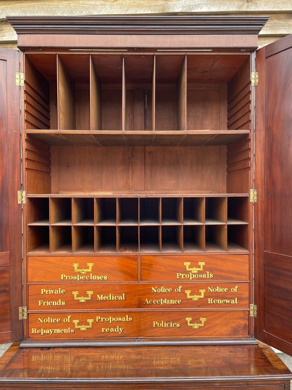 A late eighteenth-century George III mahogany estate cabinet featuring upper panel doors above drawers with gilded alphabetical lettering. View XVI