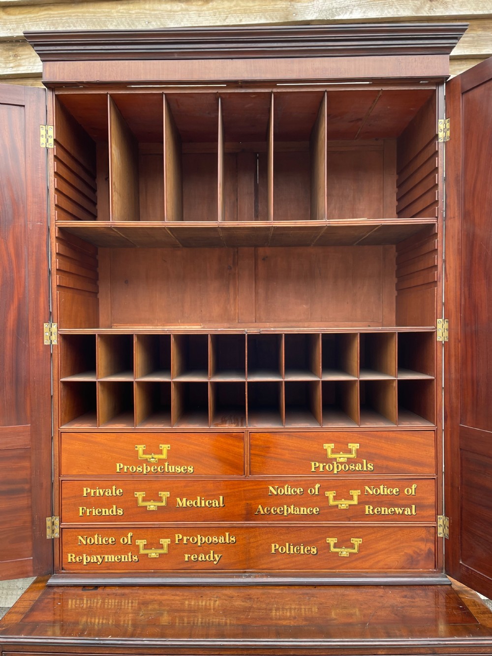 A late eighteenth-century George III mahogany estate cabinet featuring upper panel doors above drawers with gilded alphabetical lettering. View XVII