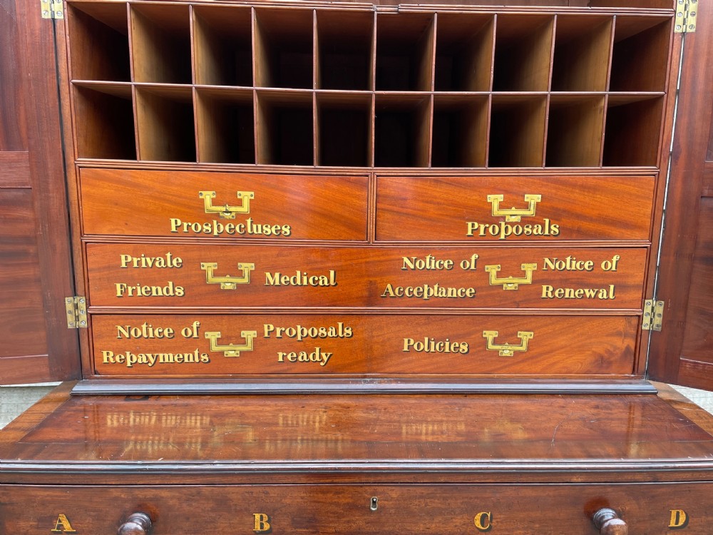 A late eighteenth-century George III mahogany estate cabinet featuring upper panel doors above drawers with gilded alphabetical lettering. View XIX