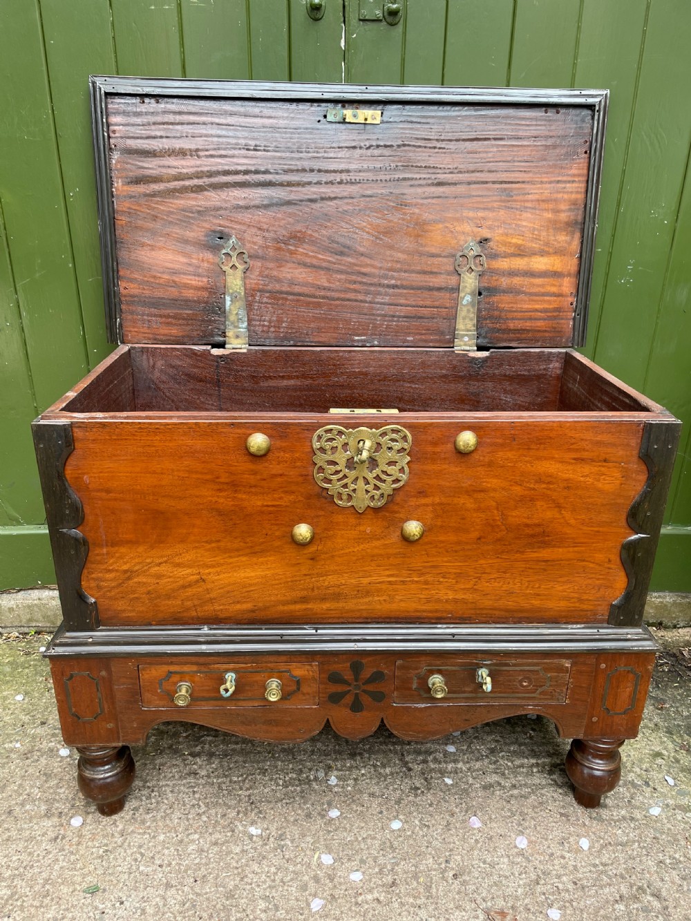 A 19th-century Dutch colonial teak and ebony chest with a pierced brass escutcheon, mounted on a two-drawer base with turned feet. View III