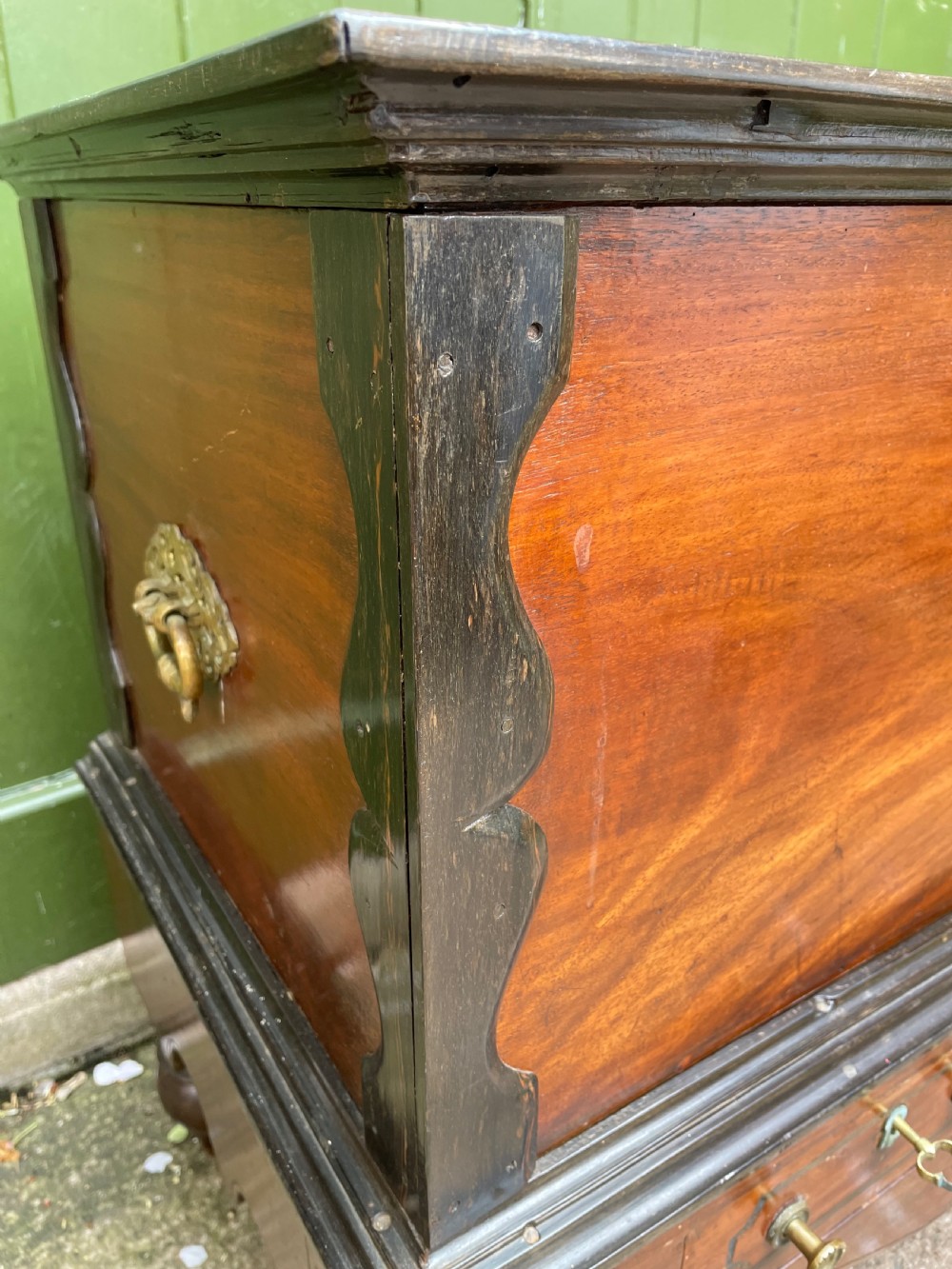 A 19th-century Dutch colonial teak and ebony chest with a pierced brass escutcheon, mounted on a two-drawer base with turned feet. View V