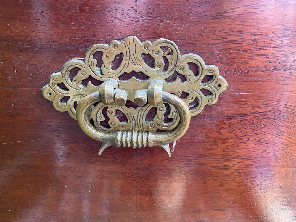 A 19th-century Dutch colonial teak and ebony chest with a pierced brass escutcheon, mounted on a two-drawer base with turned feet. View IX