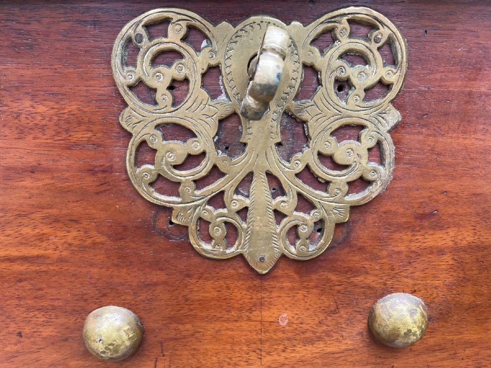 A 19th-century Dutch colonial teak and ebony chest with a pierced brass escutcheon, mounted on a two-drawer base with turned feet. View XIII