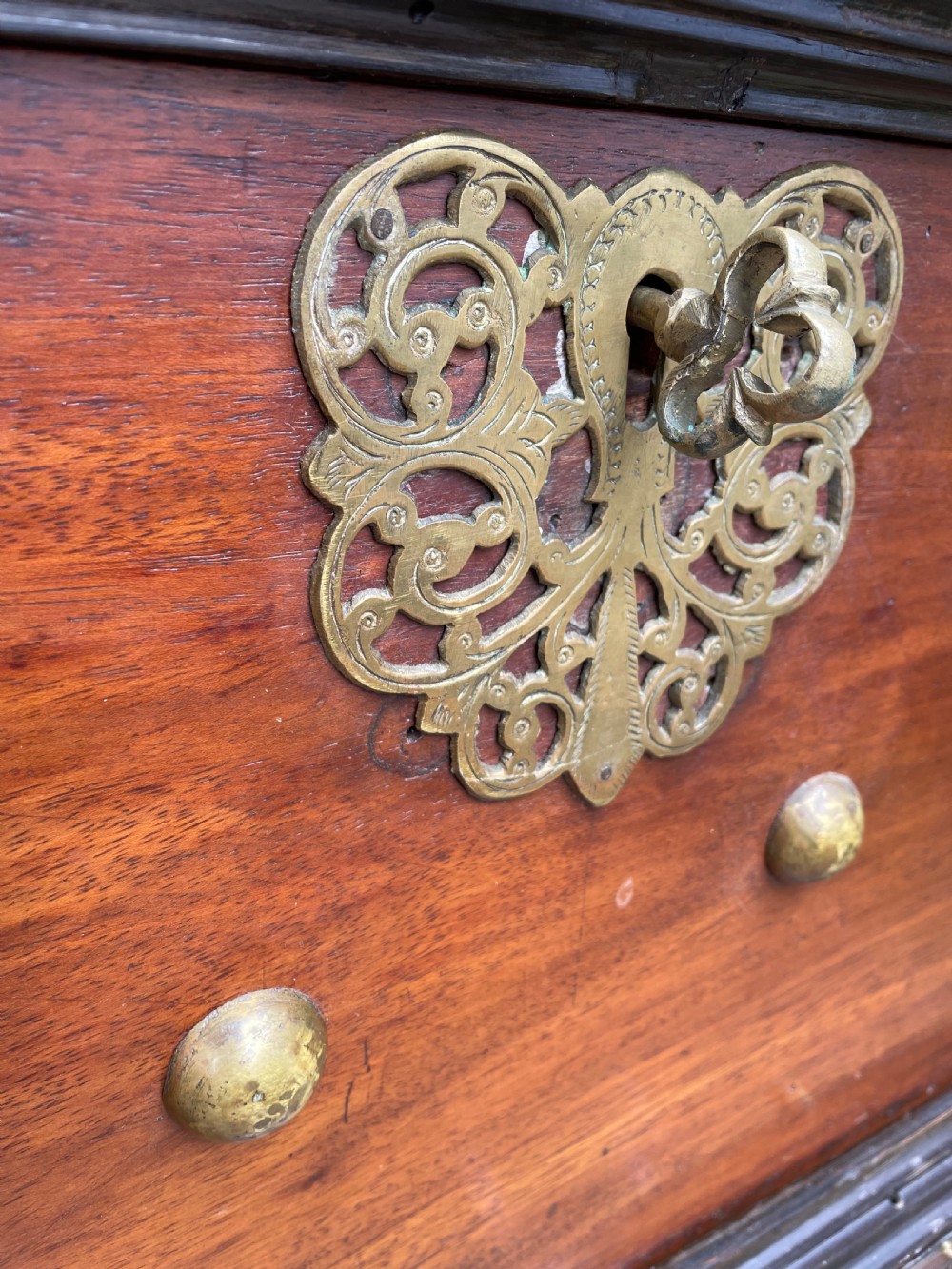 A 19th-century Dutch colonial teak and ebony chest with a pierced brass escutcheon, mounted on a two-drawer base with turned feet. View XIV