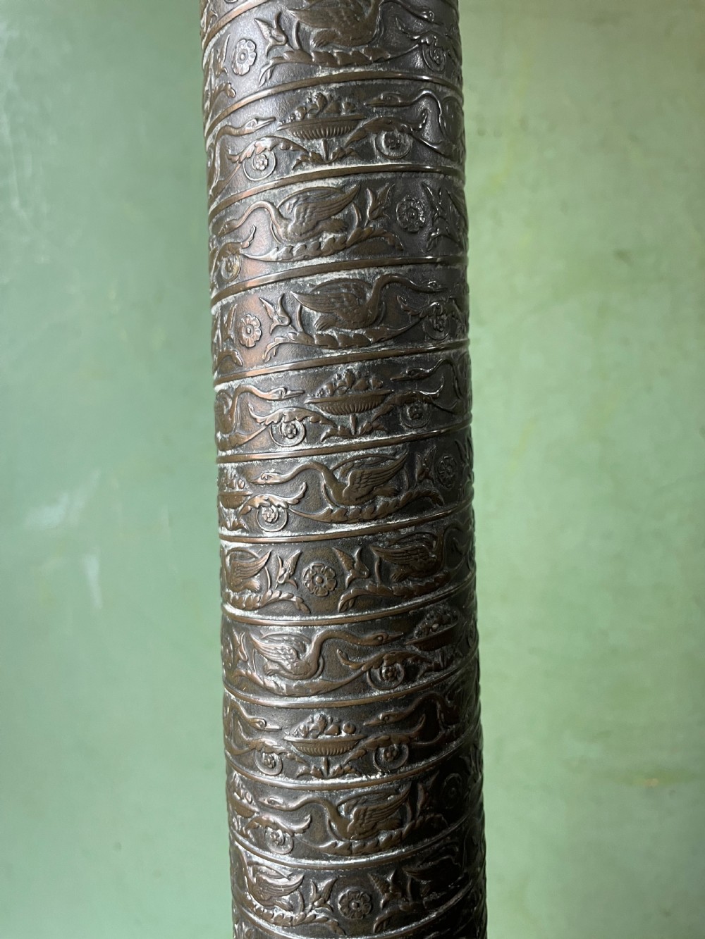An early nineteenth-century patinated brass table lamp featuring a Corinthian capital, embossed shaft, and winged relief figure on a square stepped base. View VIII